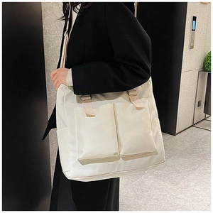 Detail of adjustable strap and front pockets on beige high-capacity canvas tote bag