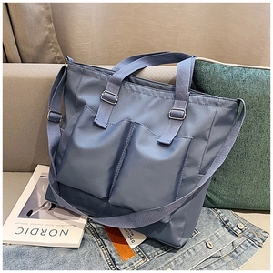 Detail of blue canvas tote bag with dual front utility pockets on a light sofa