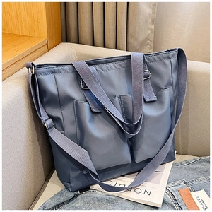 Detail view of large canvas tote bag with double front pockets and adjustable strap