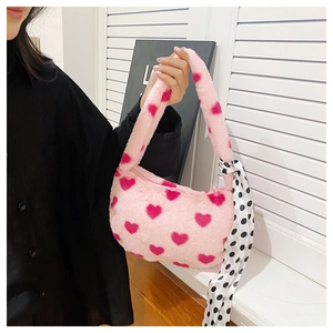 Detailed shot of pink plush handbag with red heart patterns and polka dot silk scarf