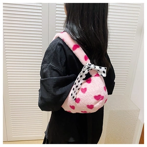 Detail of pink plush heart tote bag with a polka dot silk ribbon on the handle