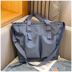 Detail of greyish blue nylon tote bag with functional pockets and adjustable shoulder strap