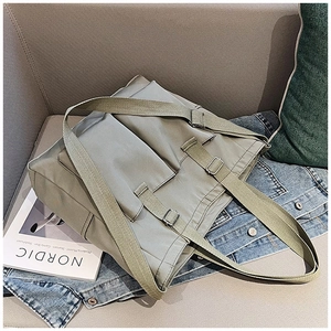 Detail of adjustable strap and outer pocket on light green canvas tote bag in a cozy setting