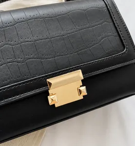 Gros plan du sac à main noir motif crocodile avec fermoir et clous en métal doré poli