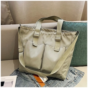 Detail of gray-green nylon tote bag with dual front pockets and adjustable strap