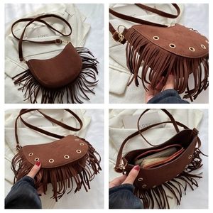Détails d'un sac demi-lune en daim marron avec franges et œillets métalliques
