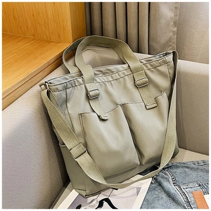 Close-up of olive green nylon tote bag with front pockets on a cozy sofa background