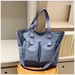 Detail of blue canvas tote bag with large front pockets and adjustable shoulder strap