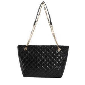 Borsa tote nera lucida trapuntata con catene dorate su sfondo bianco neutro
