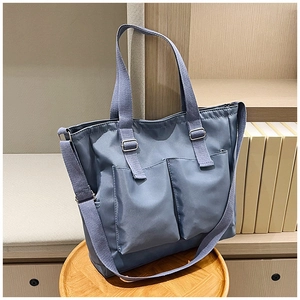Detail of blue nylon tote bag with dual front pockets and adjustable silver metal hardware