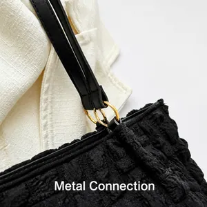 Detailed close-up of black pleated tote bag with dual gold metal ring strap connections