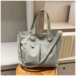 Grey nylon tote bag showing adjustable wide shoulder strap and spacious front pockets