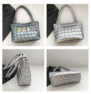Detail view of silver quilted tote bag featuring letter embroidery and large capacity