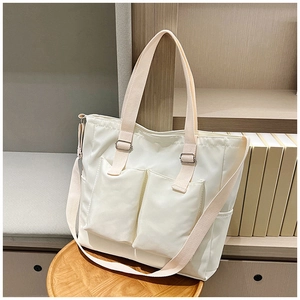 Detail of off-white canvas tote bag featuring double front pockets and adjustable straps