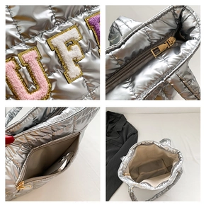 Detail of silver quilted tote bag showing plush letter patches and smooth zipper closure