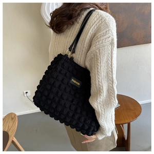 Detail of black puffy bubble texture tote bag with fashion tag and gold metal ring