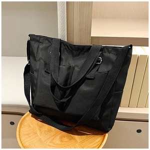 Detail showing the multi-pocket design and adjustable shoulder strap of the black tote bag