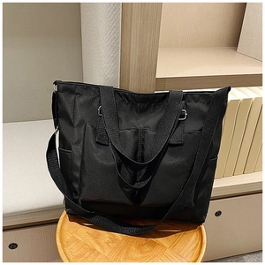 Detail of black canvas tote bag with two front pockets and adjustable shoulder strap