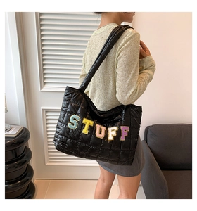 Detail of black quilted tote bag with colorful sequined STUFF lettering embroidery