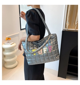 Detailed view of silver quilted tote bag with colorful STUFF embroidery and shoulder straps