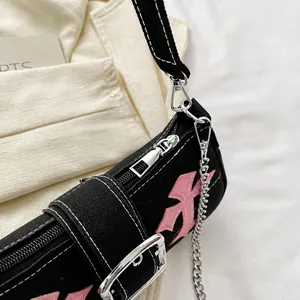Close-up of smooth silver zipper and pink embroidery on black canvas baguette bag