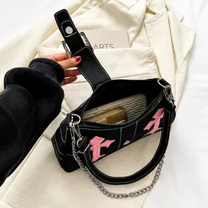 Detail view of the black canvas shoulder bag interior with pink cross embroidery and chains