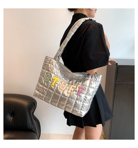 Detailed view of silver quilted tote bag featuring colorful STUFF towel embroidery