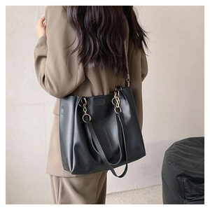 Model draagt een zwarte PU-leren shopper met grote capaciteit en schouderbanddetails
