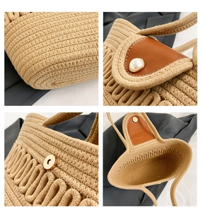 Detail showing the brown leather flap, pearl clasp, and textured woven fabric of the handbag