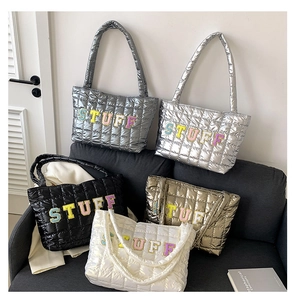 Detailed display of colorful STUFF embroidery on quilted glossy tote bags in five colors