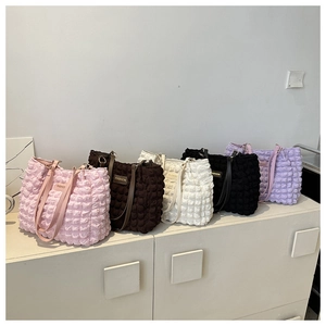 Detail of five colorful bubble textured tote bags showing wrinkled fabric and leather tags