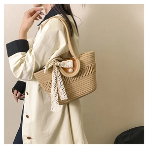 Close-up of straw woven tote bag featuring pearl closure and white lace ribbon detail