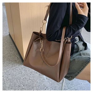Detail van de grote donkerbruine shopper met gouden ketting en verticale sierstiksels