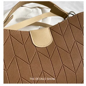 Detail showing geometric stitching and contrast beige handle on brown leather handbag