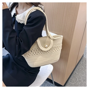 Close-up of beige woven texture with a large pearl clasp and light leather flap detail