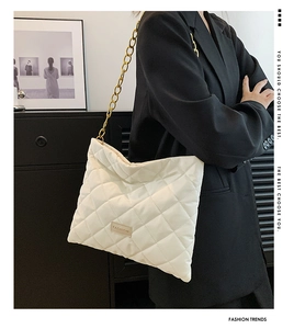 Close-up of white quilted puffer shoulder bag with chunky gold chain and fashion label