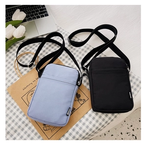 Detail of compact nylon sports crossbody bags in black and purple with adjustable straps