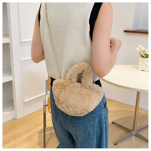Detalle de un mini bolso de peluche en forma de corazón con cadena dorada para invierno