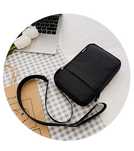 Close-up of black nylon crossbody phone bag with adjustable strap and IDEAS woven label