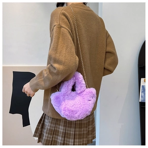 Detalle de cerca de un bolso de felpa morado suave con cadena sobre un suéter marrón