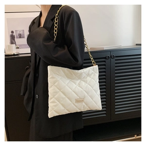 Detail of white quilted crossbody bag with chunky gold chain strap and fashion label