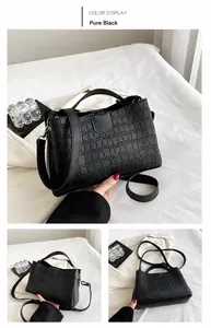 Detailed view of pure black faux crocodile leather handbag with adjustable strap