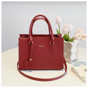 Detail of red quilted PU leather tote bag with gold heart charm and fine stitching