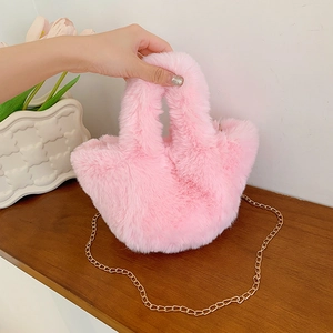 Bolso de peluche rosa con cadena de metal dorado sobre una mesa de madera