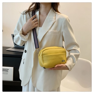 Litchi texture crossbody bag in bright yellow with a wide striped fabric shoulder strap