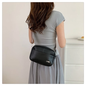 Close-up of black lychee grain camera bag with silver metal buckle on a shoulder strap