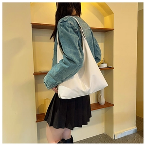 Détail d'un sac cabas blanc minimaliste en cuir avec coutures verticales porté par un modèle