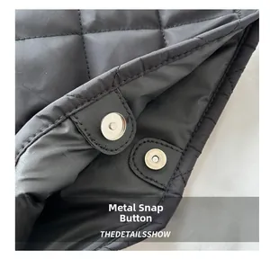 Detail of silver magnetic snaps on black quilted oxford cloth tote bag showing hardware quality