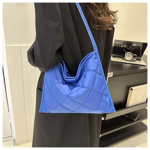 Close-up of bright blue quilted tote bag with large diamond stitching and padded texture