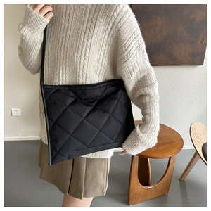 Detail of black quilted crossbody bag showing soft diamond stitching and premium fabric texture
